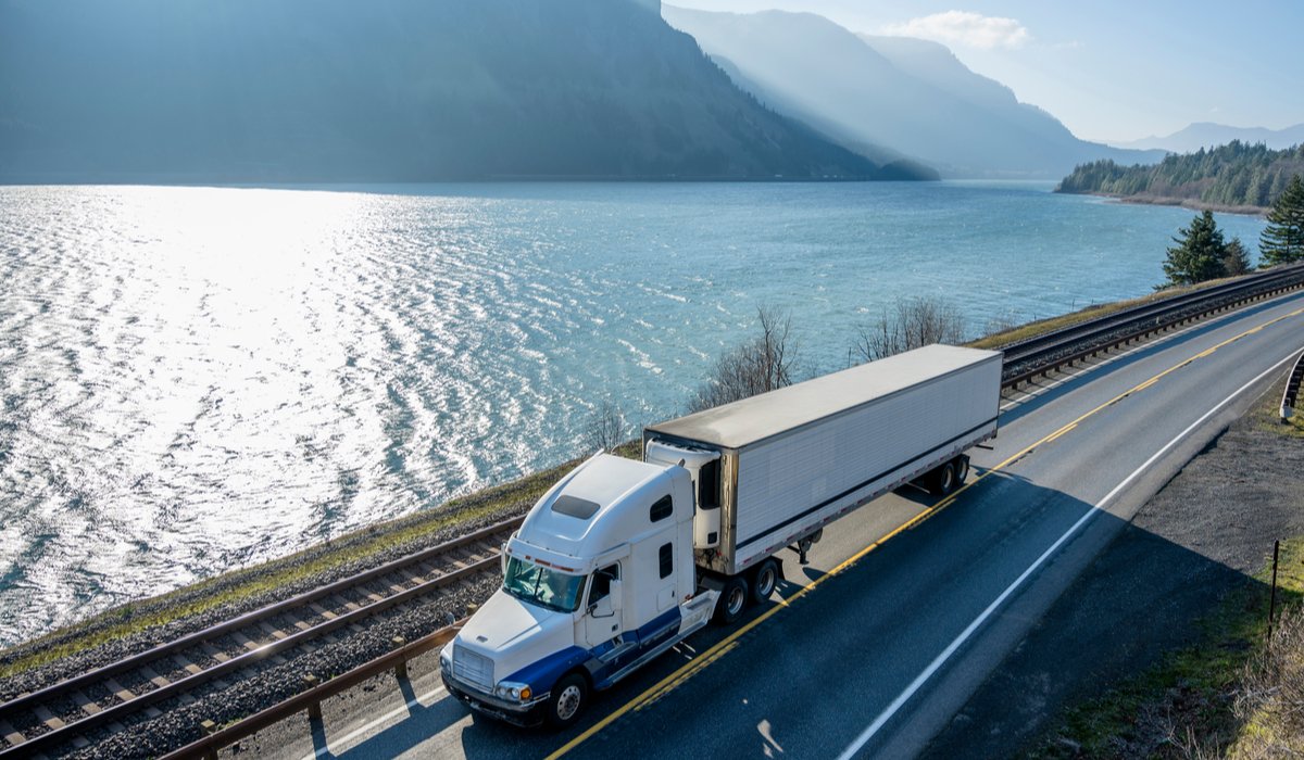 A semi truck with a refrigerated trailer running along the Columbia River