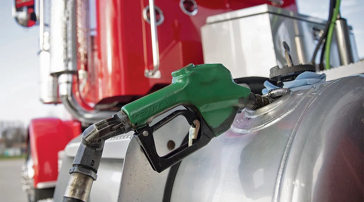 A green diesel nozzle filling the tank of a semi truck